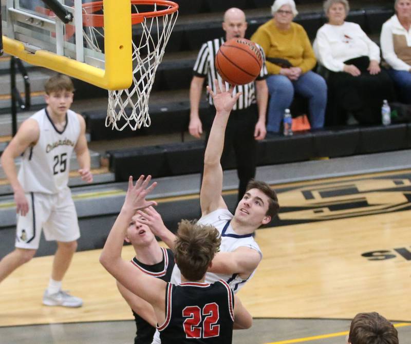 Marquette's Denver Trainor eyes the hoop over Woodland's Zandar Redke and teammate Jon Moore during the Tri-County Conference Tournament on Thursday, Jan. 25, 2024 at Putnam County High School.