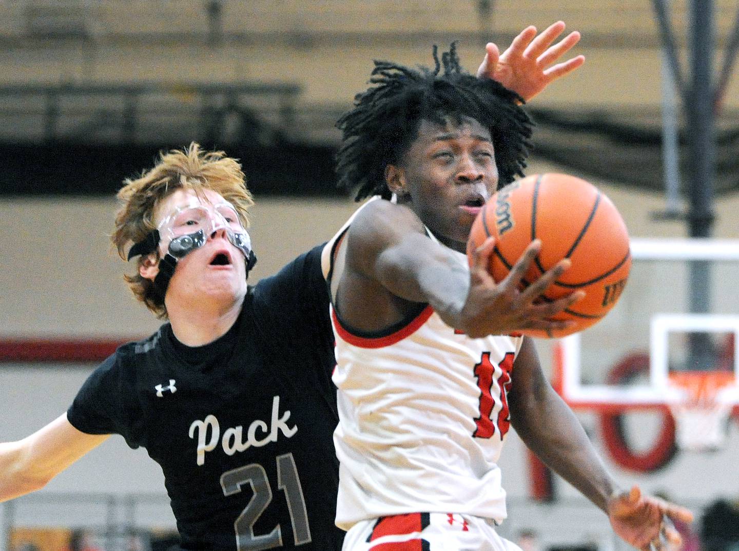 Yorkville's Kaevian Johnson (10) takes a hit to the head from Oswego East defender Andrew Pohlman (21) during a varsity basketball game at Yorkville High School on Friday, Feb. 9, 2024.