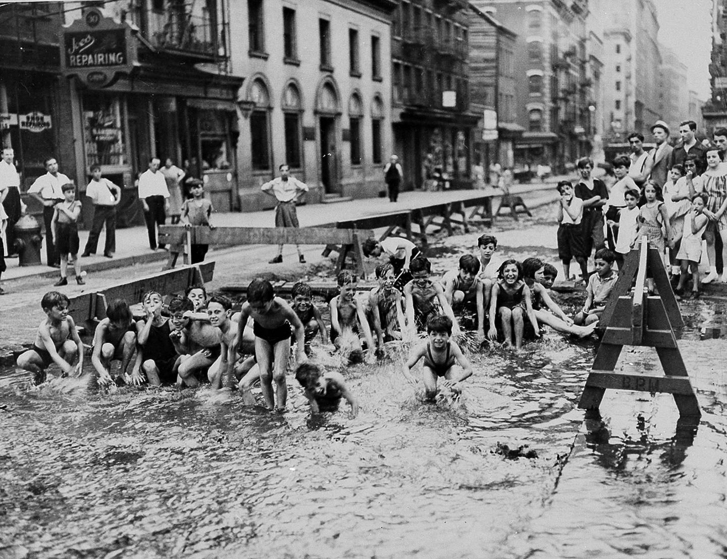 Children on Mulberry Street in the Lower East Side turned a WPA street excavation site into a temporary swimming hole using water from a fire hydrant as temperatures rose to the highest point in New York City history on July 9, 1936.