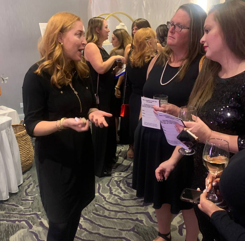 Ashley Rapp, left, owner of Hello! Staging+Organizing, talks to attendees about the raffle items offered by her business at CASA of McHenry County's Little Black Dress celebration and fundraiser on Oct. 10, 2024, in Crystal Lake.
