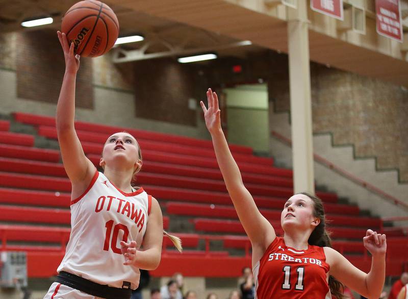 Ottawa's Ella Schmitz runs in for a layup past Streator's Kora Lane during the Lady Pirate Holiday Tournament last season at Kingman Gym.