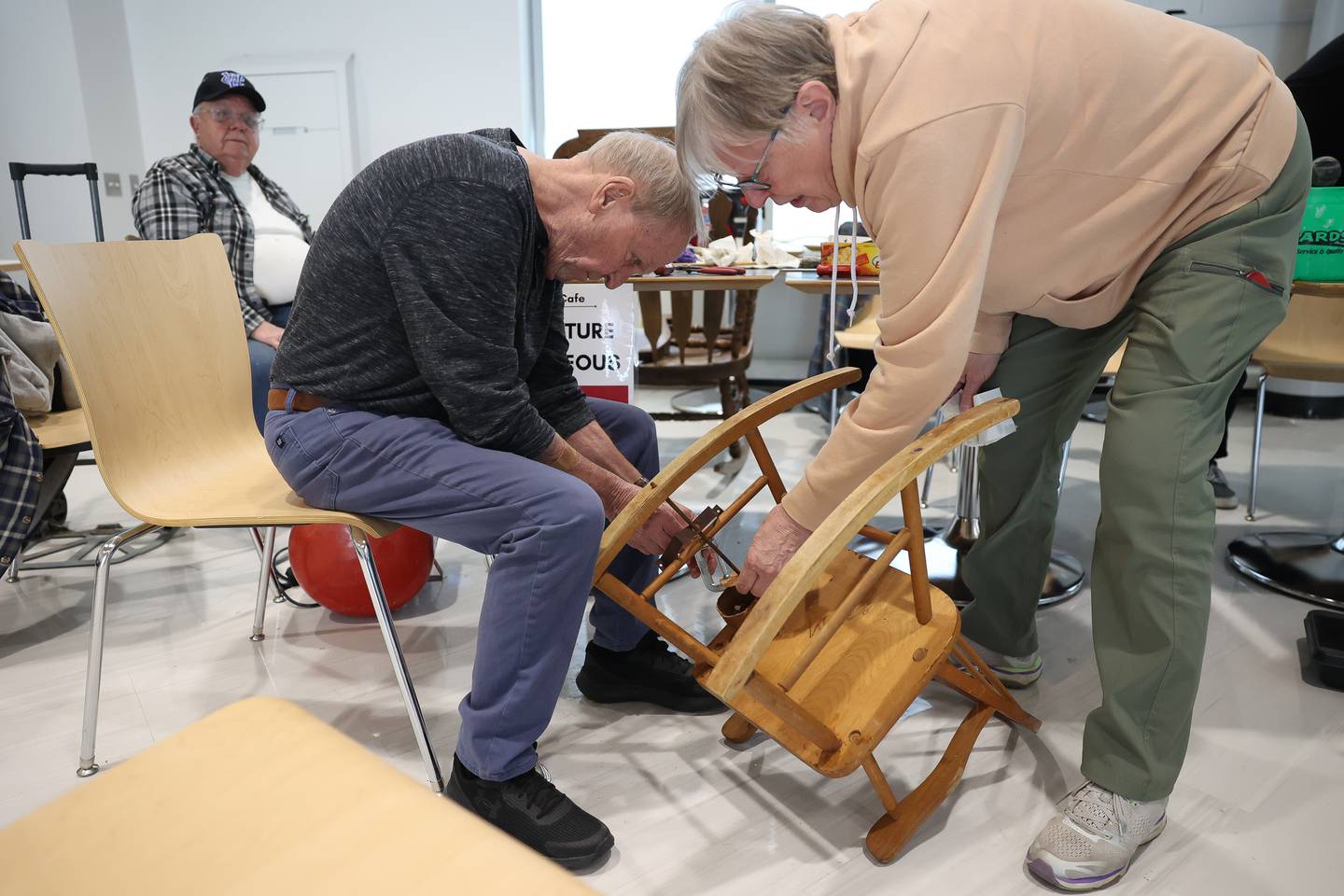 Pat Asher, a retired JJC teacher, left, repairs Cindy Weber’s childhood musical rocking chair during the Repair Cafe event at the Joliet Junior College Romeoville campus on Saturday, April 13, 2024.