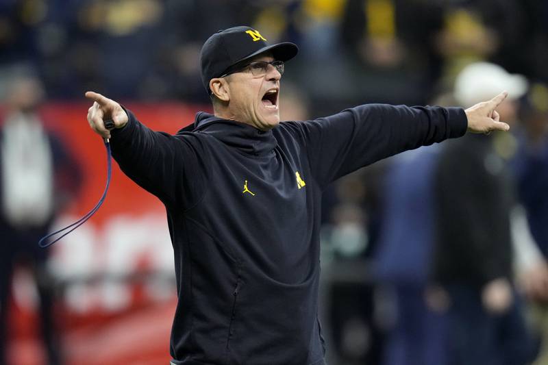 Michigan head coach Jim Harbaugh directs his team during warmups before the Big Ten championship against Iowa, Saturday, Dec. 4, 2021, in Indianapolis.