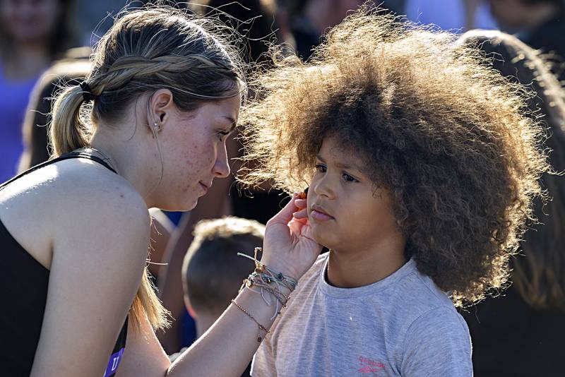 Dixon High School cheer squad member Evelin DeLeon paints a basketball on JJ Harrington’s, 7, face Thursday, August 31, 2023. The squad provided face painting and temporary tattoos to the kids who attended the PTO back to school fun day.