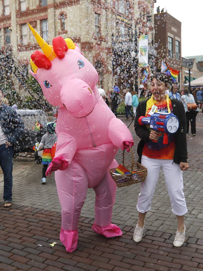 Dr. Raymond Pryor, dressed in a unicorn costume and Torrie Benson-Pryor, from Secure Alliance Counseling, dances with bubbles after marching in the Woodstock PrideFest Parade Sunday, June 11, 2023, around the historic Woodstock Square.
