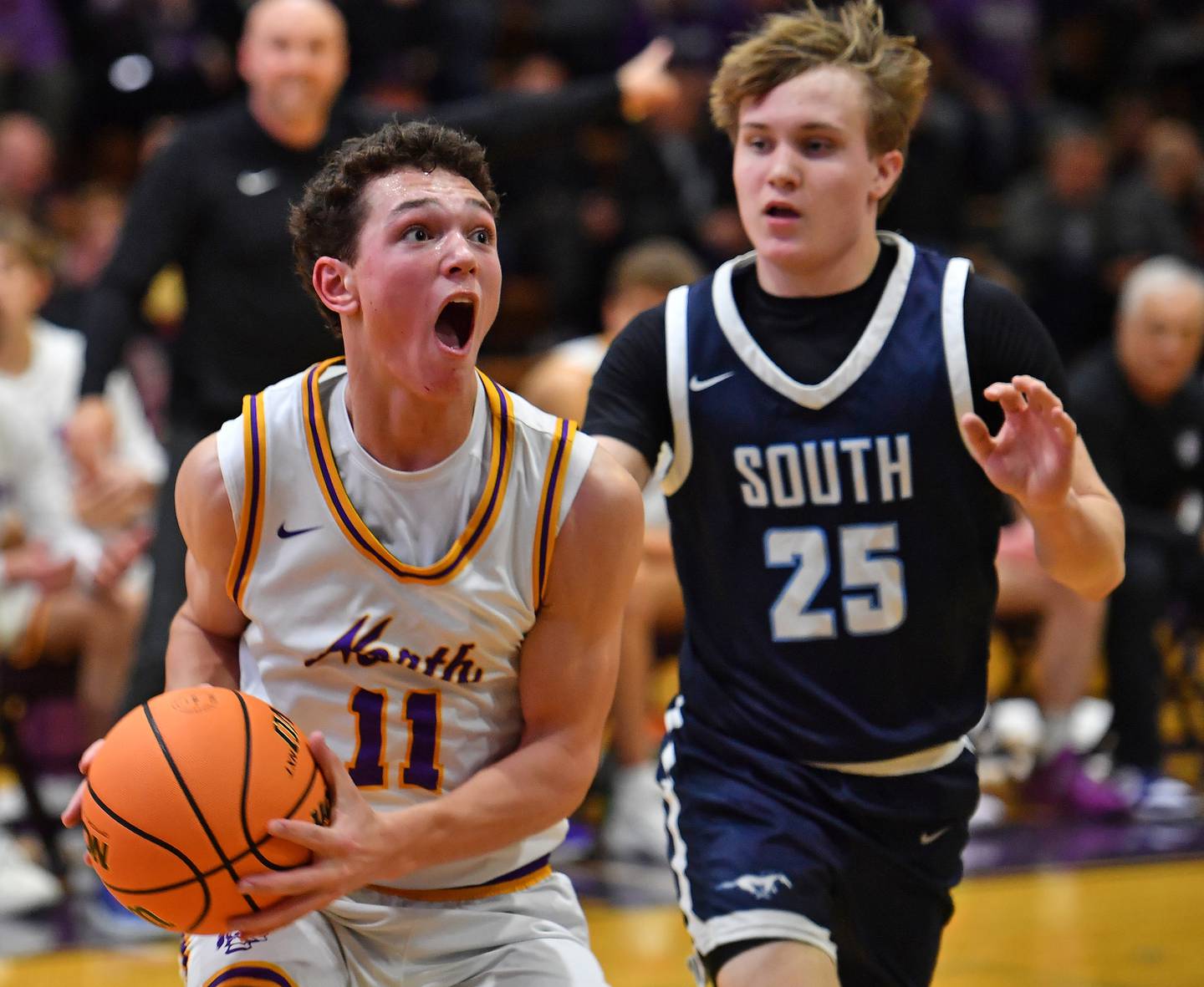 Downers Grove North’s Connor Crowley (11) drives the baseline as Downers Grove South’s Gavin Cigrand (25) defends during a game on December 20, 2025 at Downers Grove North High School in Downers Grove.