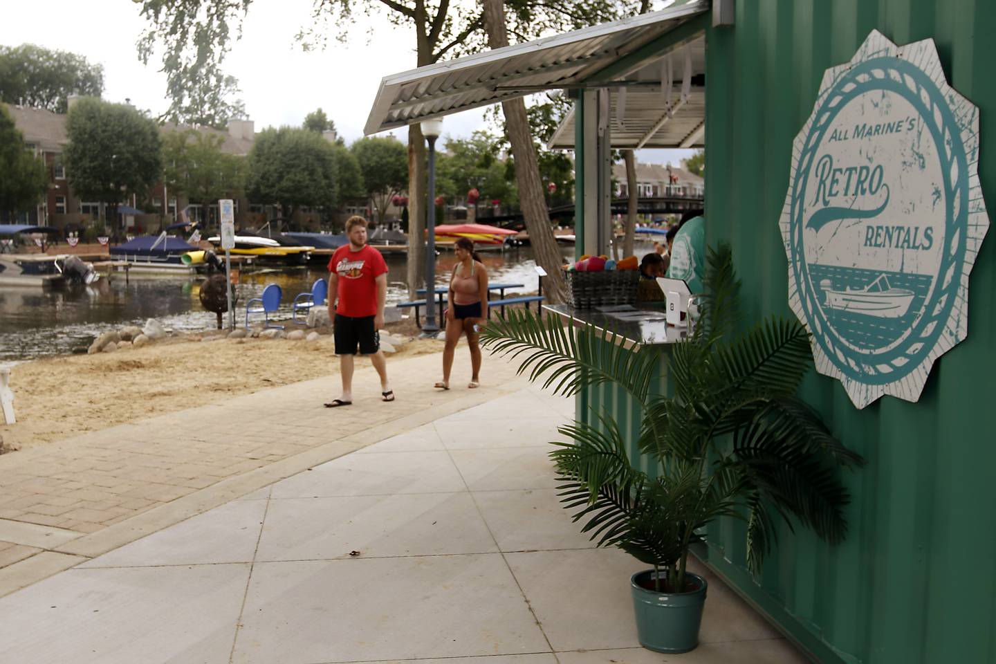People walk past All Marine’s Retro Rentals and the Retro Retreat Beach Bar in McHenry’s Miller Point Park.