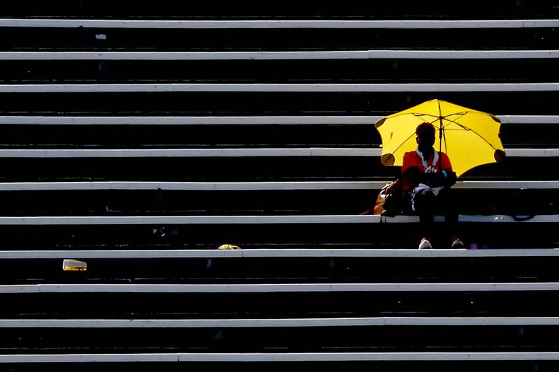 A women uses an umbrella as she watches the ItHSA Class Boys State Track and Field Championship meet on Saturday, May 25, 2024, at Eastern Illinois University in Charleston.