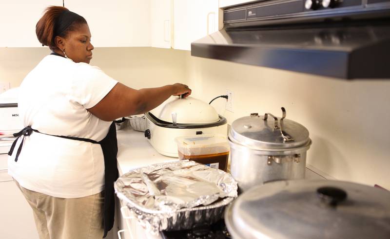 Shaw Local 2011 file photo - Adrian Coburn moves from one pot to the next as she puts together a plate for someone getting a Thanksgiving day meal at New Hope Missionary Baptist Church in DeKalb, Ill. on Thursday, Nov. 24, 2011.