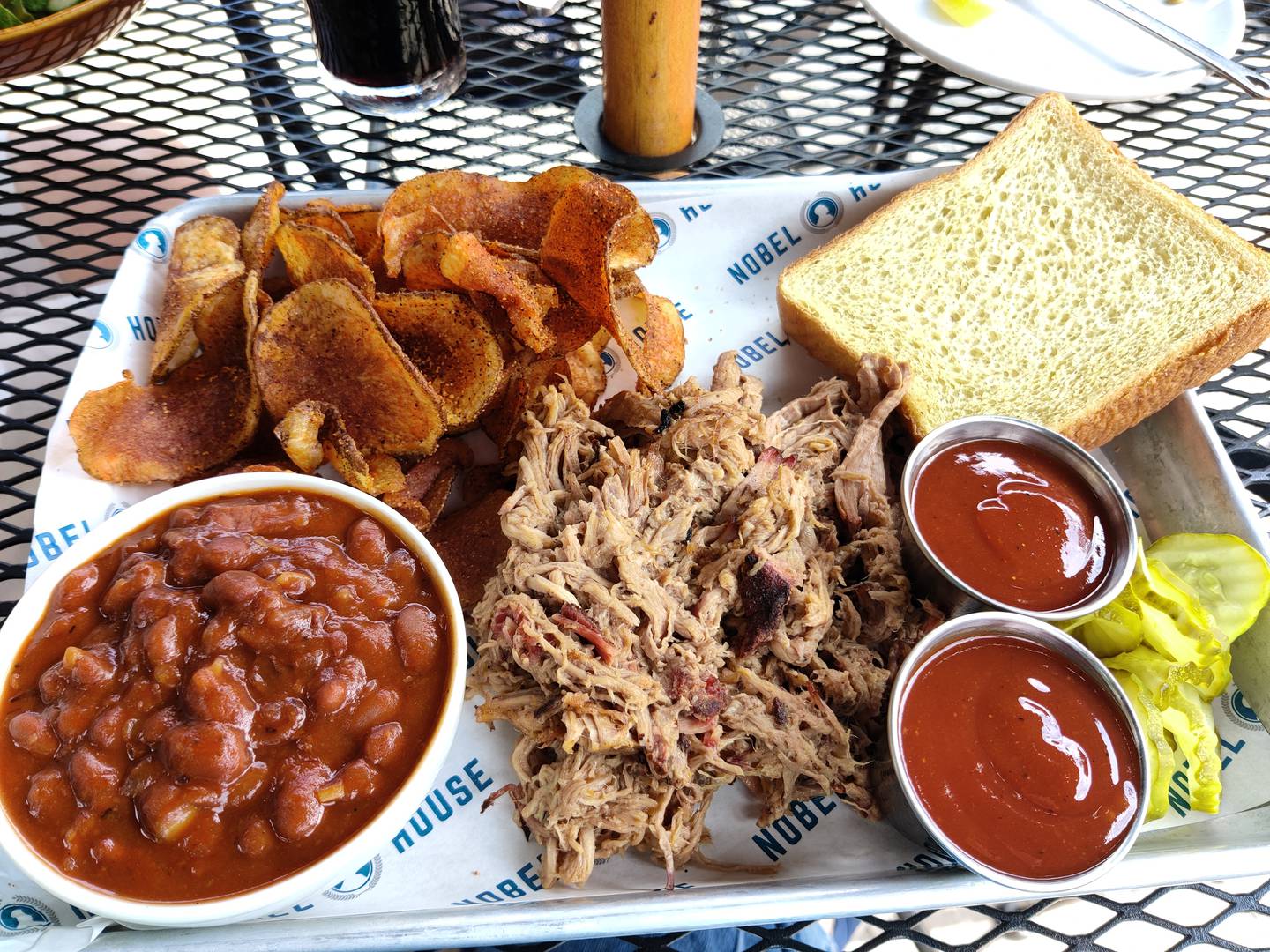 This order of Meat and Two features pulled pork, baked beans and homemade chips, with pickles and Texas toast.