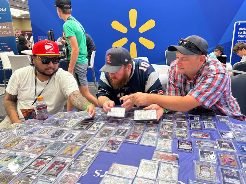 From left, T Yim, Matt Sheehan and Kyle Hansen of Fat Cat Exclusives in Merrimac, Mass., look at cards for a potential trade during the 45th National Sports Card Convention at the Donald E. Stephens Convention Center in Rosemeont Saturday, Aug. 2, 2025.