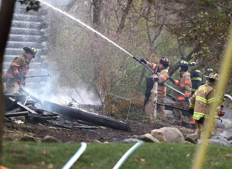 Firefighters put water on a smoldering house that was destroyed by fire Thursday, Nov. 13, 2025, near Shabbona Grove Road in Shabbona. Several local departments responded to the general alarm structure fire.