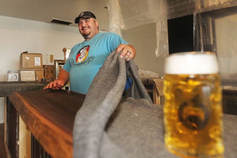 Joshua Grubbs, president/brewer, takes off the blanket covering the black walnut bartop featured at the Black Lung Brewing Company’s new location under construction in Fox Lake on Monday, June 26, 2023. The small brewery from Round Lake Beach has started a Kickstarter fundraiser called, Black Lung Expansion to Fox Lake. The grand opening for Black Lung Brewery Fox Lake is on July 22nd from 3-5pm. 
Image by Candace H. Johnson for Shaw Local News Network