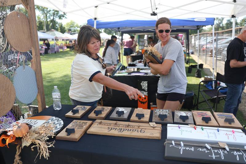 Erica Bartleman, owner of EJ Creations, right, helps Lori Dela Fuente with her purchase at the Crest Hill Lions Luau and Car Show on Sunday, Sept. 1, 2024 in Crest Hill.