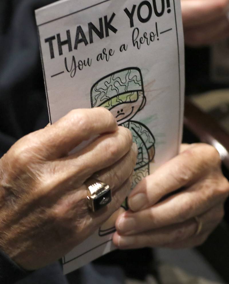 U.S. Marine World War II veteran Johns Rickerd holds a “Thank You” card made by first graders during the Veterans Day event on Monday, Nov.11, 2023, at the Upper Campus of McHenry High School.