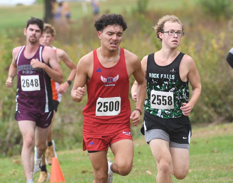 Oregon's Daniel Gonzalez (center) grimaces as he runs at the Amboy Columbus Day Cross Country Invitational held at Shady Oaks Country Club near Amboy on Monday, Oct. 13, 2025.