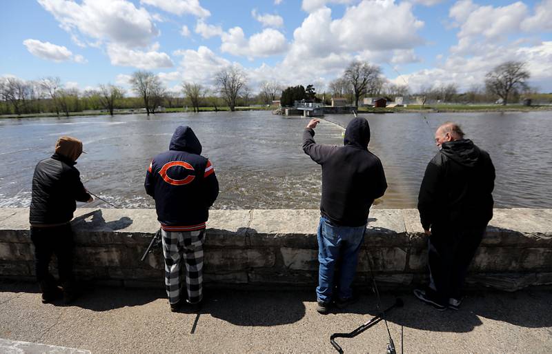 Water rushes over the McHenry Dam while people fish on Sunday, April 19, 2026, as the Fox River continues to rise.