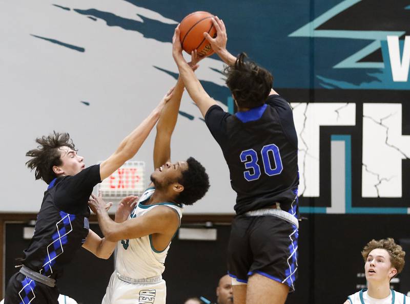 Woodstock's Collin Greenlee (left)  and Spencer Cullum (right) grab the basketball away from Woodstock North’s Darnell McMillerduring a Kishwaukee River Conference boys basketball game on Friday, Jan. 5. 2024, at Woodstock North High School.