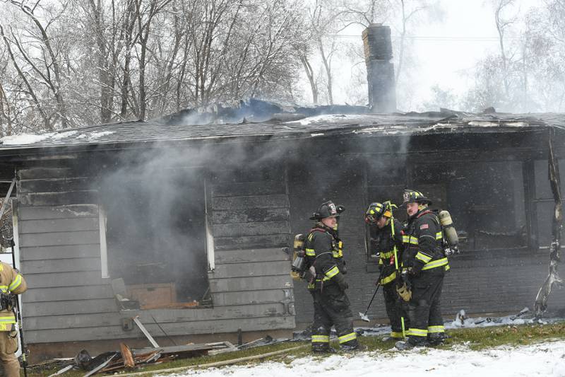 Oregon firefighters stand by the charred remains of a home in Byron after several area fire departments battled the fire at 115 W. Third Street Saturday morning. One woman was declared dead after being found outside the home after a power line fell on the house causing to become "electrified," a fire official said.