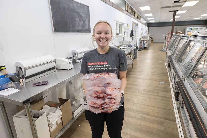 Emma Cunniff carried an armful of New York strip steaks at The Butcher Shop on Wednesday, May 10, 2023.
