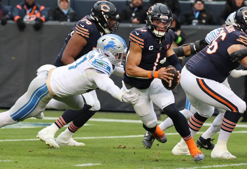 Chicago Bears quarterback Justin Fields scrambles away from Detroit Lions defensive end Aidan Hutchinson during their game Sunday, Dec. 10, 2023 at Soldier Field in Chicago.