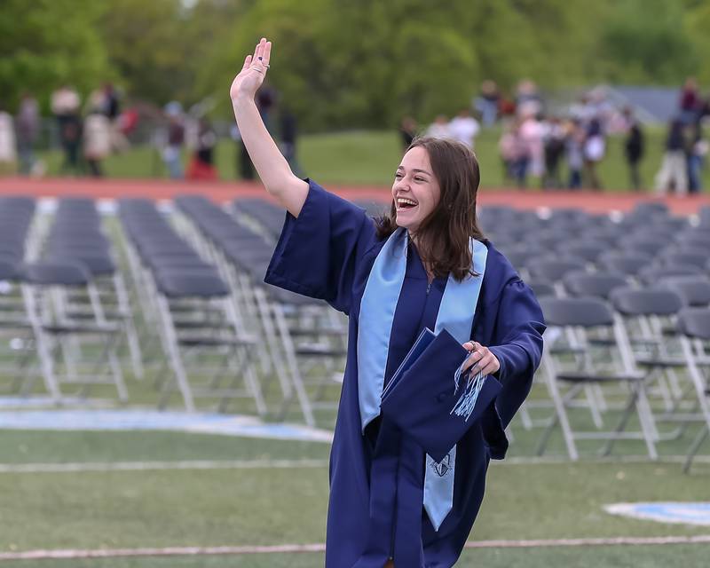 A graduate waves to her family after the Downers Grove North graduation ceremony at the school on Sunday, May 22, 2022