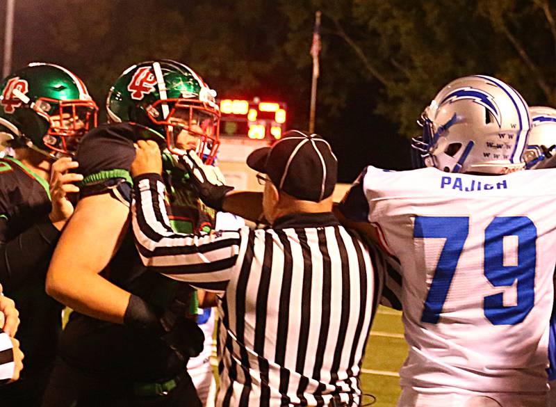 A referee breaks up a scuffle between L-P's Nikolas Belski (72) and Woodstock's Copper Pajich (79) on the L-P sideline during the Homecoming football game on Friday, Sept. 30, 2022 at Howard Fellows Stadium in Peru.