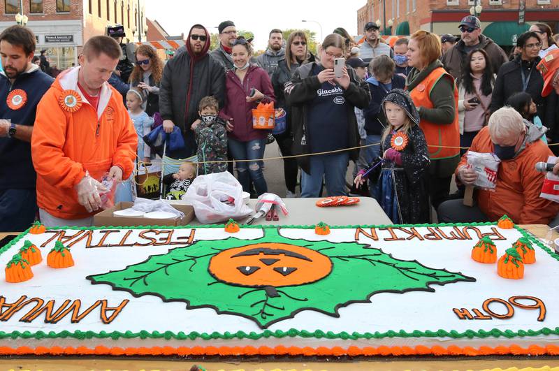 People wait for the cake-cutting ceremony Wednesday, October 27, 2021, on North Maple Street during the first day of the Sycamore Pumpkin Festival. The two cakes were donated by the Sycamore Hy-Vee.