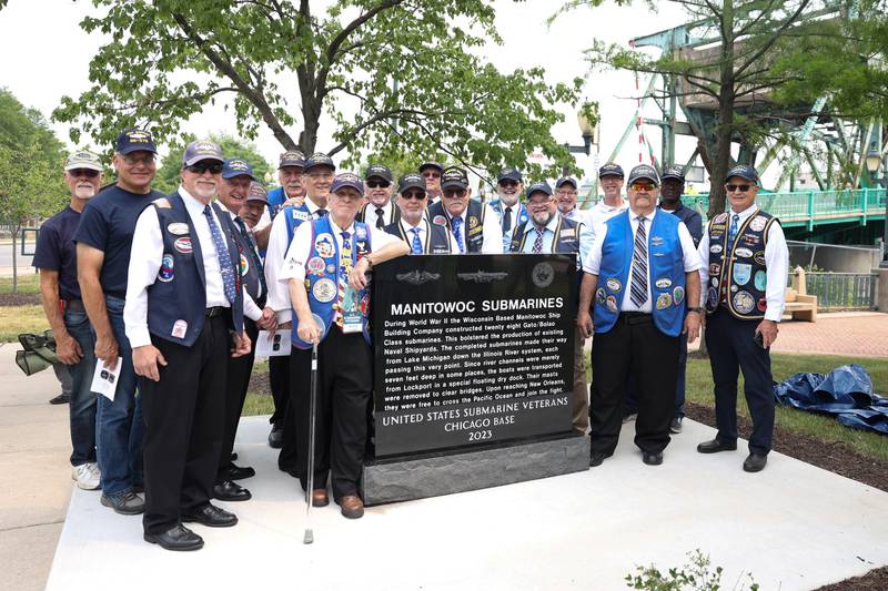 Members of the United States Submarine Veterans Chicago Base pose in front of the new memorial at a special Flag Day ceremony dedicating a memorial to remember the 28 World War II Submarines that traveled through Joliet on their way to the Pacific theater in Bicentennial Park on Wednesday, June 14, 2023 in Joliet.