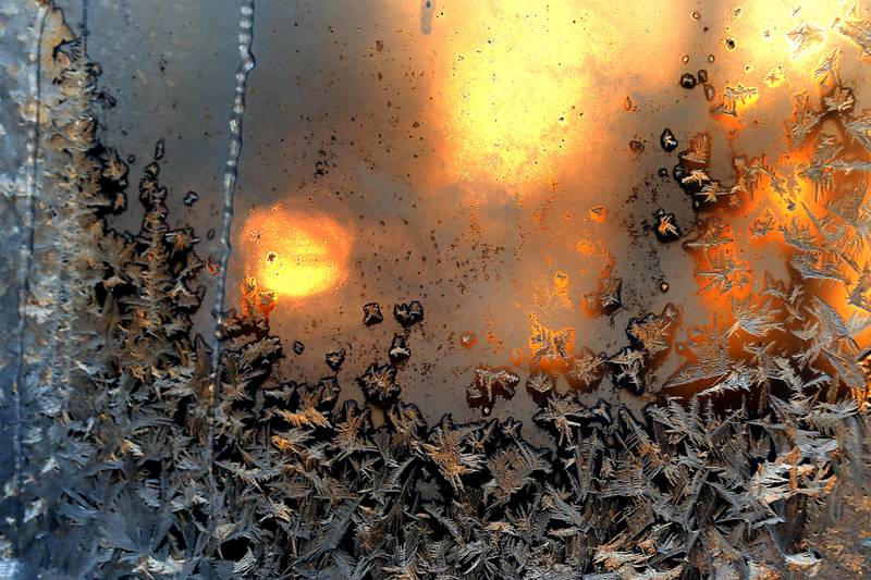 The setting sun shines throw frost on a window of a home.