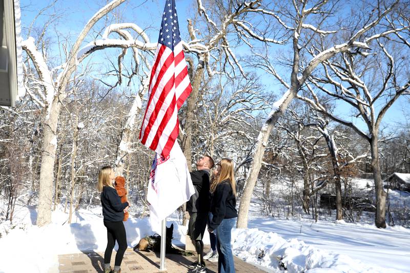 Retired U.S. Army Chief Warrant Officer 2 Patrick Scrogin, along with wife Alexa, service dog, Kiowa, and children Wyatt, Paige and Kaylee, raise American and Army flags during a dedication for his family’s newly constructed, specially adapted smart home in St. Charles on Thursday, Jan. 18, 2024. The mortgage-free home was made possible by the Gary Sinise Foundation.