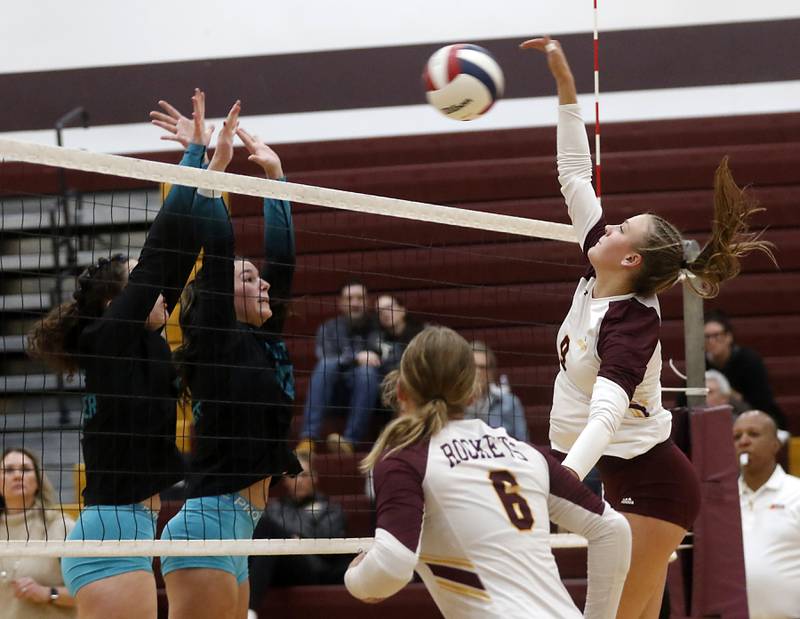 Richmond-Burton's Reagan Wisniewski (right) spikes the ball into the block attempt of Woodstock North's Gabriella Schefke (center) and Ava Kardaras (right) during a Kishwaukee River Conference volleyball match on Wednesday, Oct. 15, 2025, at the Richmond-Burton High School in Richmond.