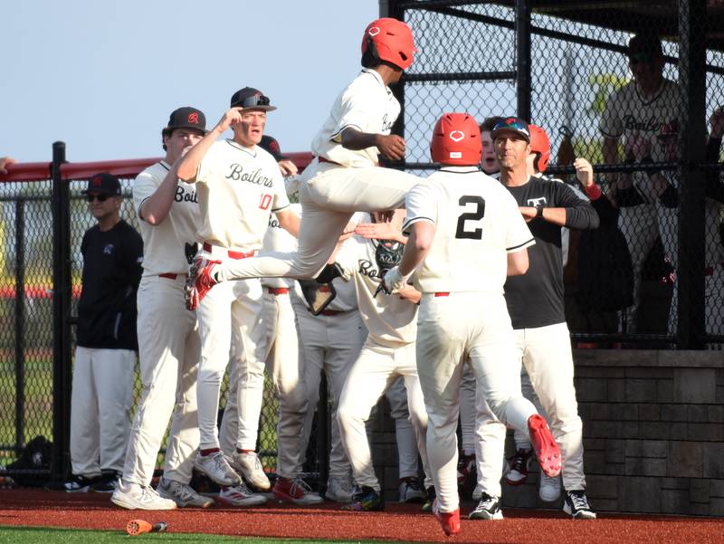 Members of the Bradley-Bourbonnais baseball team greet a leaping Byron Summral at the dugout after he scored a run during a home game against Stagg Friday, May 8, 2026.