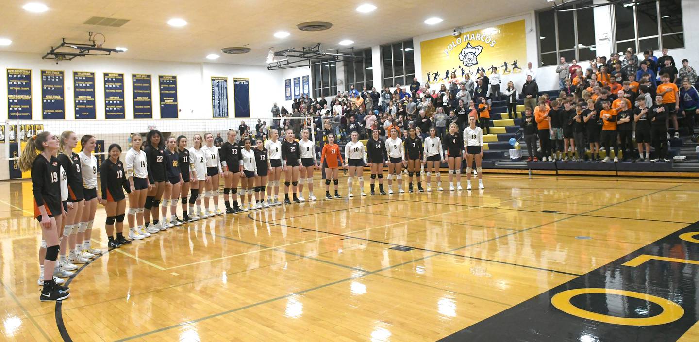 Members of the Polo and Milledgeville volleyball teams hold hands and stand together for the National Anthem prior to the start of their Oct. 13 match in Polo. The Marcos, along with Polo High School staff and students, held a 50/50 raffle, silent auction, and bake sale during the match with with proceeds benefiting two Milledgeville teens who were critically injured during an auto accident on Sunday, Oct. 9. Marcos fans were also asked to wear black and orange, Milledgeville's colors.