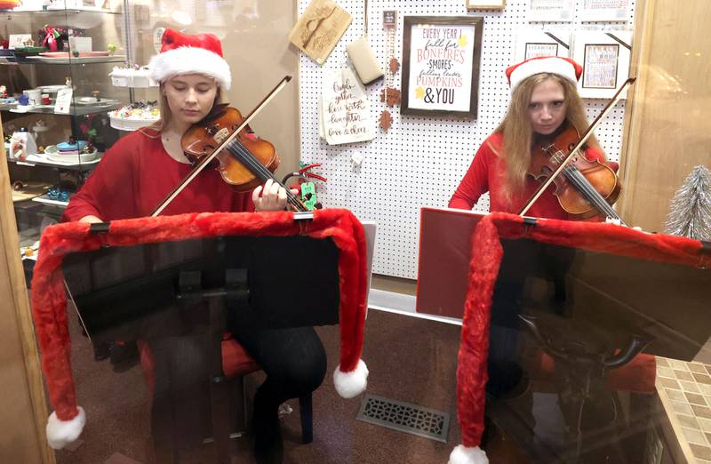 Emma Fredericks, (left) 17, and Eva Peterson, 16, both from Sycamore, perform in the wind of Lizzy’s Pink Boutique Friday, Nov. 18, 2022, during the Sycamore Chamber of Commerce's annual Moonlight Magic event in downtown Sycamore.