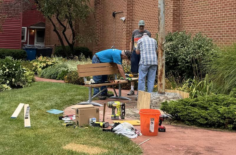 Rick Martino and two parishioners from Immaculate Conception in Morris work on fixing the concrete around the base of the flag pole where the plaque honoring Morris's World War I veterans is displayed.