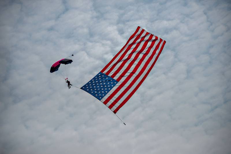 To the playing of the "Star Spangled Banner," a skydiver floats down with the U.S. flag in tow at the start of the ACCA Air Show on Saturday, July 24, 2021, at Whiteside County Airport near Rock Falls.