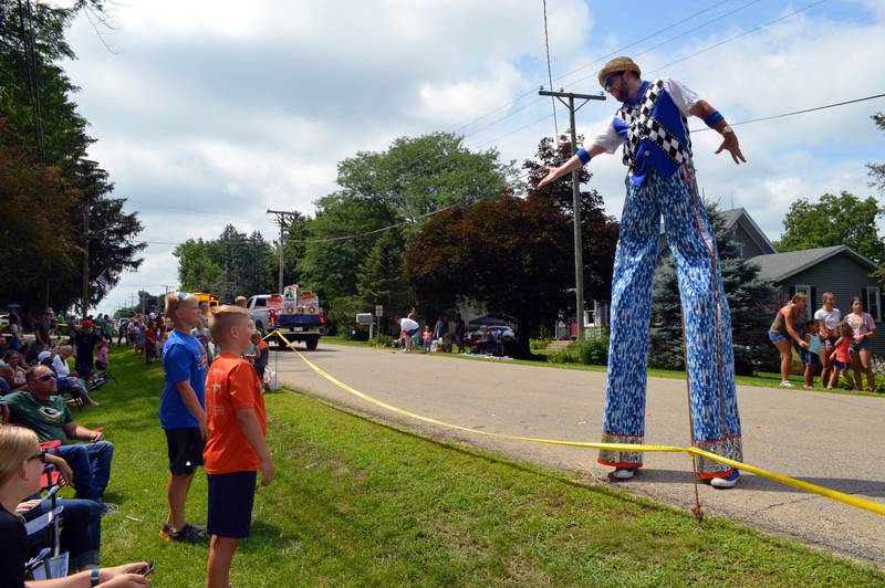 A stilt walker in the 2022 German Valley Days parade holds his hand out to Owen Gunderson, 13 (blue shirt), and Ethan Gunderson, 10 (orange shirt), both of Shannon. The parade took place on July 16.