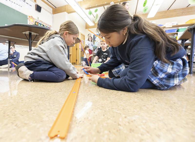 Dixon St. Anne’s students build a track to race their toy cars down Thursday, March 6, 2025. The challenge was to learn how to make their cars go faster with added weight and track changes.