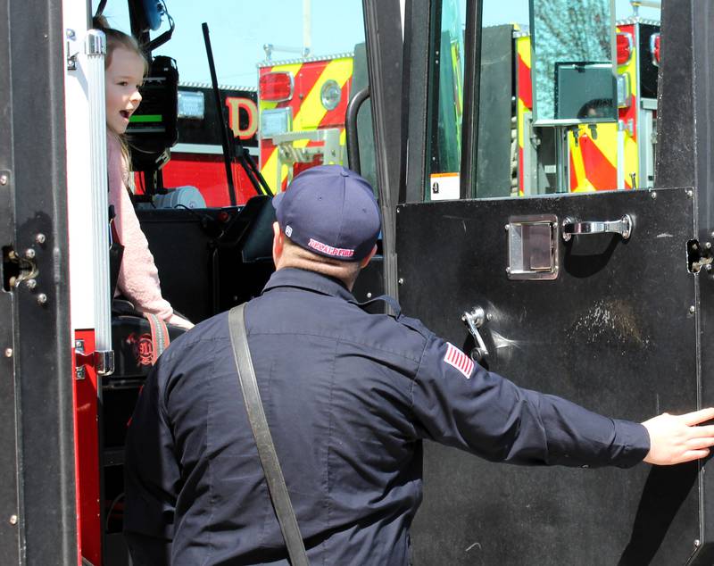 A girl sits in one of the fire engines on display outside of DeKalb Fire Station No. 4 at 1130 S. Malta Road at a grand opening event on Saturday, April 26, 2025.