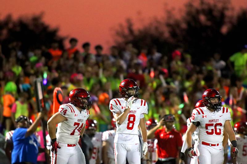 The setting sun paints the sky as Huntley’s, from left, Ryan Wabel, Colin Kalemba and Ethan Albertson trot out to face Jacobs in varsity football at Jacobs High School in Algonquin on Friday, Sept. 26, 2025.