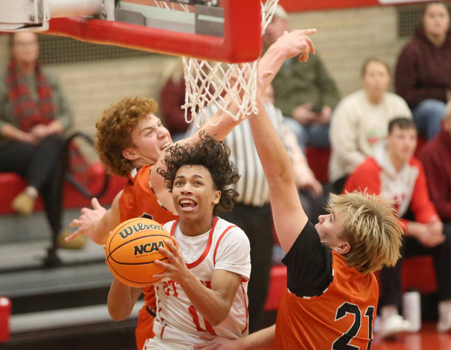 Ottawa's Hezekiah Joachim eyes the hoop while splitting Sandwich defenders Dom Rome and Noah Campbell on Wednesday, Dec. 4, 2024 in Kingman Gym at Ottawa High School.