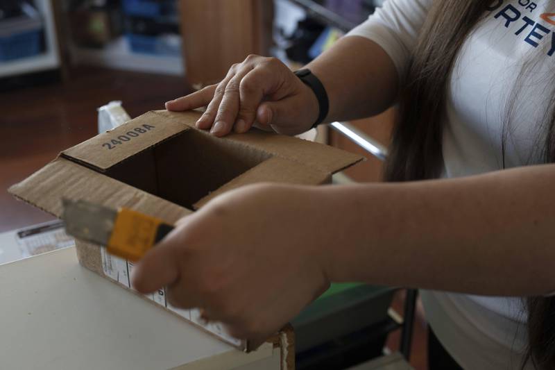 CORRECTS COMPANY NAME: Amanda Follett opens packages at A Sight For Sport Eyes, a brick-and-mortar and e-commerce store for sport goggles, Aug. 20, 2025, in West Linn, Ore. (AP Photo/Jenny Kane)