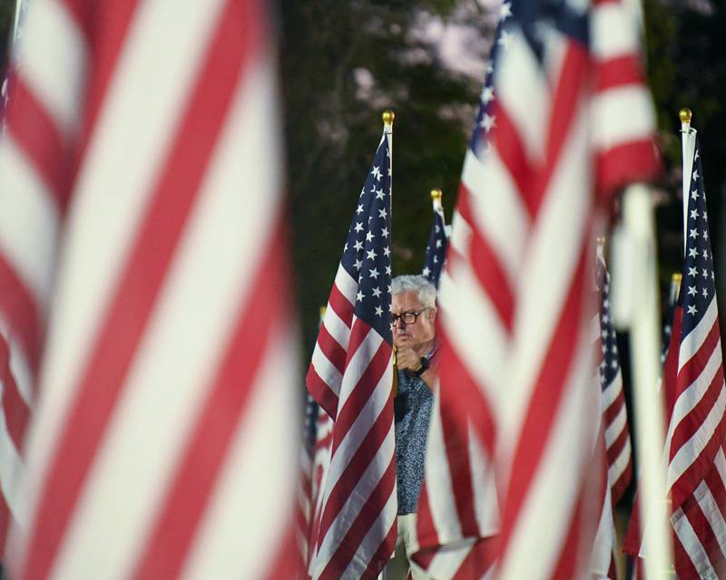 Kevin Ryan of Western Springs places a dog tag on one of 500 American flags that are on display to honor veterans, active military, first responders as well as frontline workers on Sunday Sep. 3, 2023, in honor if his family.