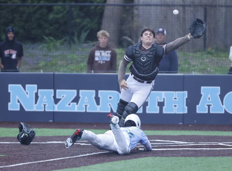 Nazareth's Jaden Fauske (21) slides into home to score the winning run as Joliet Catholic's Zachary Pomatto (34) goes for the ball during the varsity baseball game on Wednesday, April 20, 2025 between Nazareth and Joliet Catholic academies in La Grange Park.