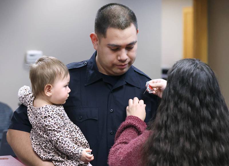 New Sycamore firefighter Carlos Aburto has his badge pinned on by girlfriend Stephanie Starks as he holds daughter Sophia Aburto following being officially sworn in Monday, April 1, 2024, during the Sycamore City Council meeting in the chambers at Sycamore Center.