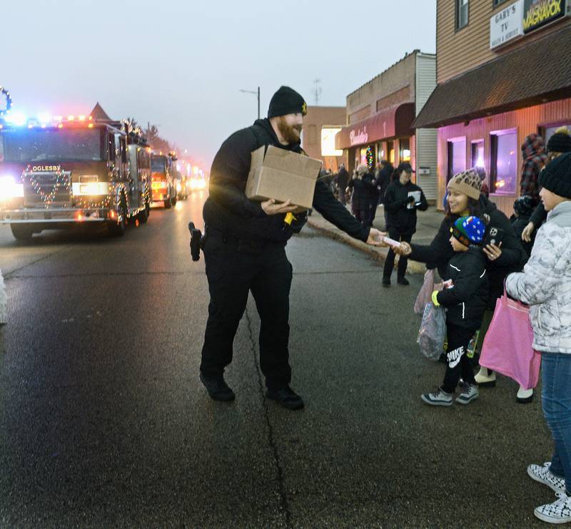 Police officers handed out gift certificates and presents along the parade route Saturday, Dec. 10, 2022, during the inaugural Winter Parade in Oglesby.