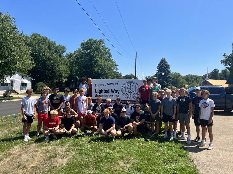 Volunteers gather around Lighted Way's sign after assisting Lighted Way move into its new location on Monday July 10, 2023.