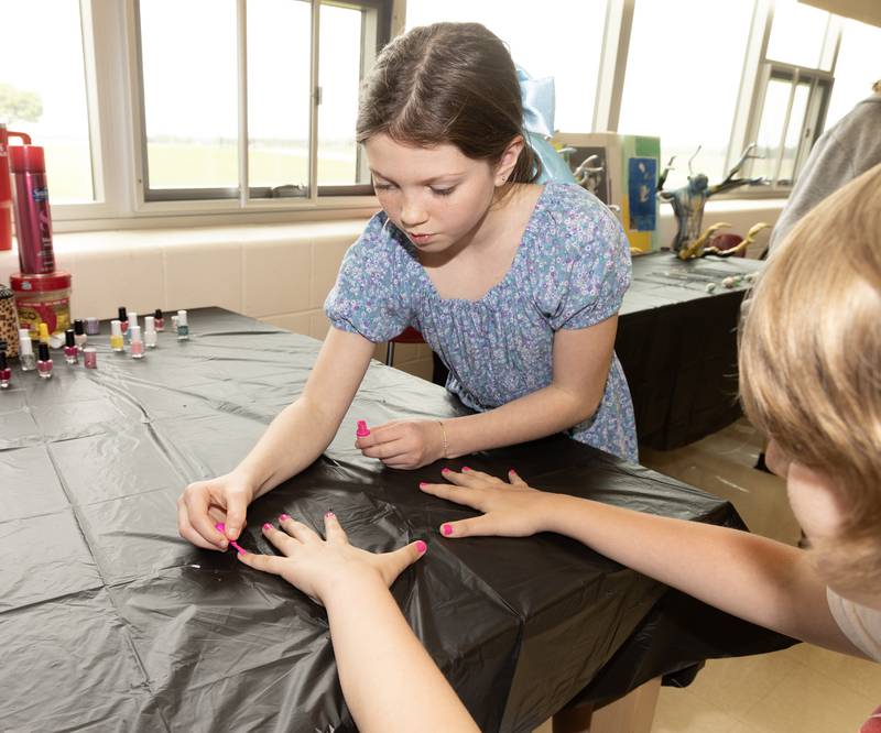 Bella-Mia Page applies pink nail polish to a fellow student. She and another classmate offer hair and nail services as part of their business, Fancy Girls.