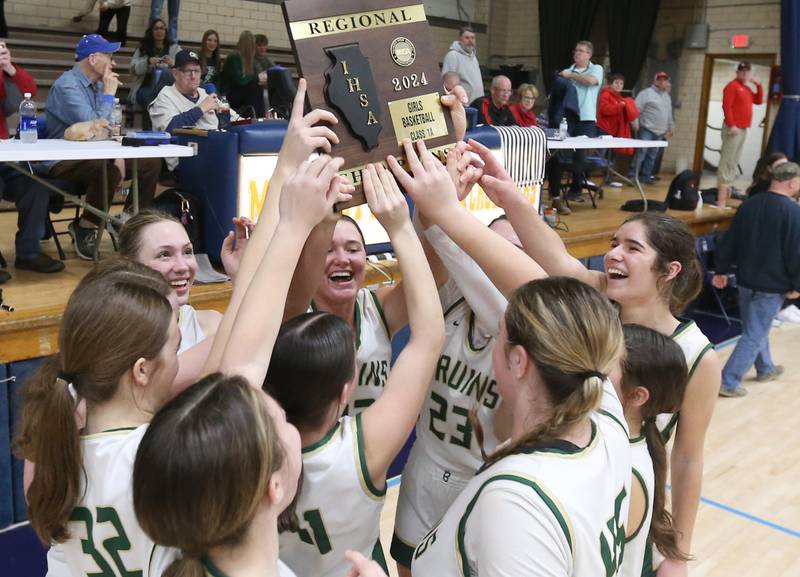Members of the St. Bede girls basketball team hoist the Class 1A Regional plaque after defeating Amboy on Friday, Feb. 16, 2024 at Marquette High School.
